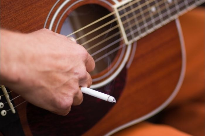 Hand with cigarette picking an acoustic guitar