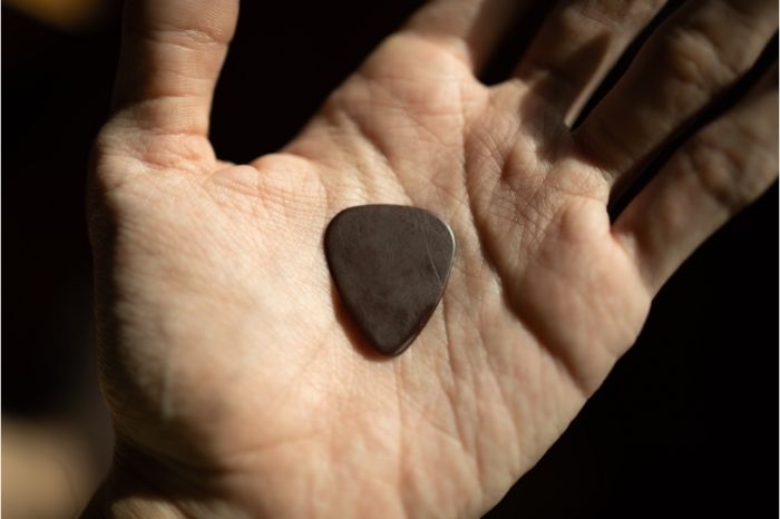 Hand holding a guitar pick that has slipped