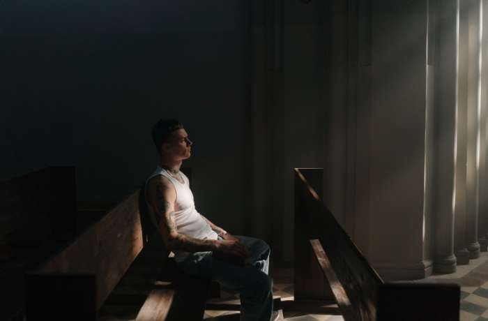 Man sitting on a church pew with rays of light coming through the window